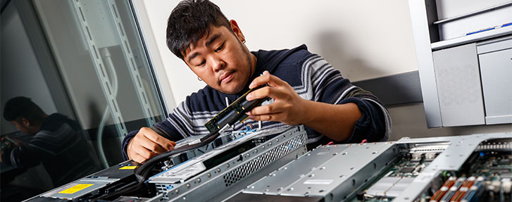 Male Student swapping out internal hardware components in computer equipment