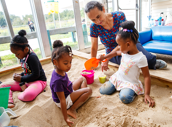 FDC staff member playing with children in sandbox